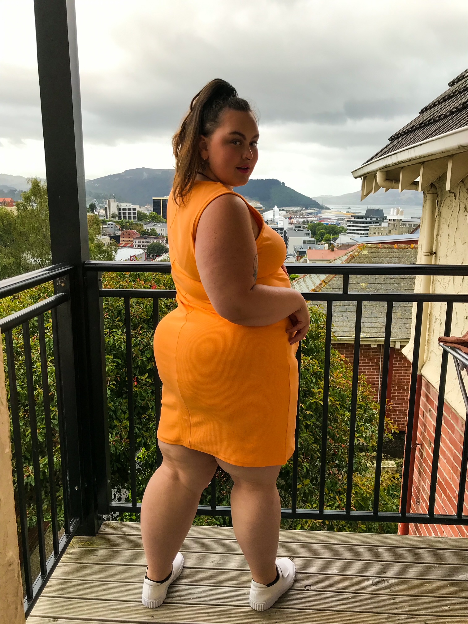 Cameron, a fat Māori babe in a bright orange bodycon dress